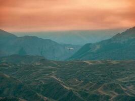 Blurred background, soft focus. Lonely eagle flying on the yellow sky over the blue mountains photo