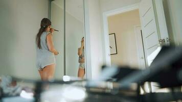 femme des stands dans de face de une miroir et s'applique maquillage à sa visage video