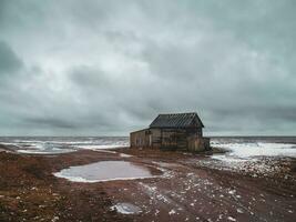 un arruinado antiguo del pescador cabaña en un auténtico pueblo en el apuntalar de el blanco mar. foto