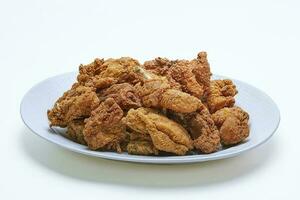 Pile of Crispy Fried Chicken with flour coating on a plate, isolated white background photo