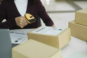 Female online business owner scan shipping label on parcel. photo