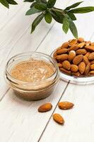 Jar of almond butter with almonds heap. Homemade almond butter, natural, healthy food. photo
