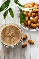 Jar of almond butter with almonds heap. Homemade almond butter, natural, healthy food. photo