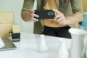 Young male online business owner using cellphone checking parcel box. photo