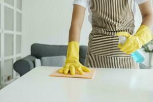 Woman cleaning and wiping table with sponge and spray at home. photo