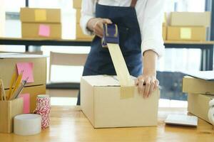 Female online business owner packing order box for dispatching. photo