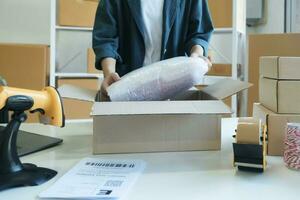 Young entrepreneur packing product in mailing box for shipping. photo