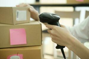 Female online business owner scanning parcel barcode tag. photo