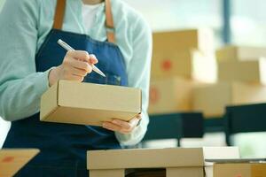 Start up small business owner writing address on cardboard box a. photo