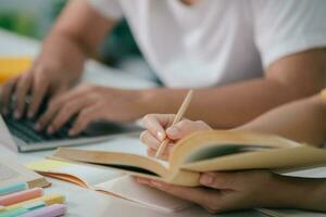 cerca arriba un asiático estudiantes son leyendo libros y estudiar, tutoría juntos. foto