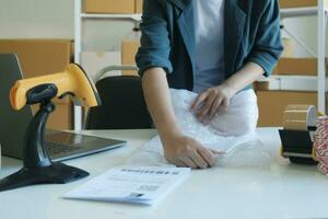 Young entrepreneur packing product in mailing box for shipping. photo