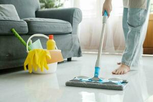 Young woman cleaning floor using mop at home. photo