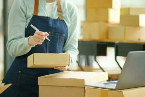 Online small business owner writing address on parcel box. photo