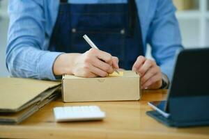 Start up small business owner writing address on cardboard box a. photo