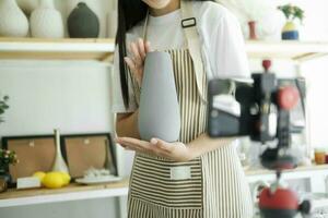Close up young asian businesswoman fashion blogger showing ceramic products with smiling face. photo