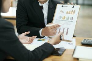 Businessmen working, discussing, analyzing using laptop and graphs. photo