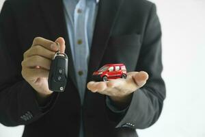 Close up hand of businessman, car dealer giving new car key to customer. photo