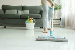 Young woman cleaning floor using mop at home. photo