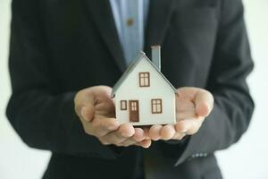 Close up real estate agent holding house model for consult the client. photo