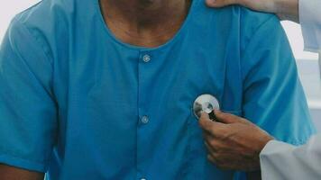 giovane medico è utilizzando un' stetoscopio ascolta per il battito cardiaco di il paziente. tiro di un' femmina medico dando un' maschio paziente un' dai un'occhiata su video
