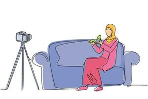 Single continuous line drawing Arabian beauty blogger is sitting at sofa, reviewing heels shoe in her hands while recording video with digital camera, tripod. One line draw design vector illustration