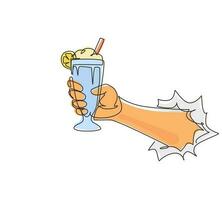 Single one line drawing hand holds glass milkshake with whipped cream through torn white paper. Cold soft drink for summer. Sweet beverage. Tasty and yummy fast food continuous line draw design vector