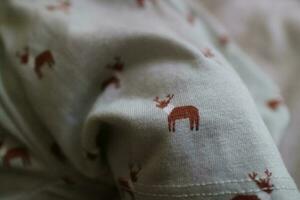 the fabric texture of a baby's dress is light green with a deer pattern photo