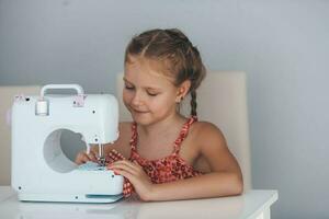 7 years old child studying work with a modern sewing machine. Hobby. photo