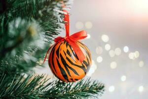 Christmas balls painted as tiger stripes on Christmas tree with a garland. 2022 is a year of the Tiger. Happy New Year . Symbol of year lunar chinese calendar tiger on Christmas ball . Copy space. photo