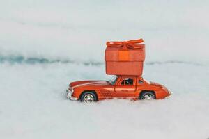 krasnodar, Rusia - diciembre 10, 2019 rojo juguete coche con un regalo en el techo, paseos en el nieve. entrega de regalos. Copiar espacio. Navidad . nuevo año. foto