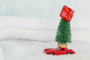 Red toy car with a christmas tree on the roof, white background. Copy space . Concept new year. photo