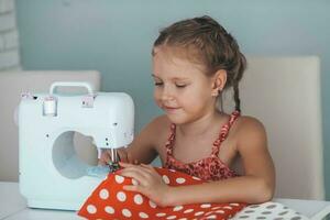 7 years old child studying work with a modern sewing machine. Hobby. photo