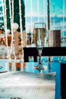 un vaso de champán en el mesa en contra el antecedentes de el bokeh de un noche restaurante. Club nocturno, celebracion, Navidad. foto