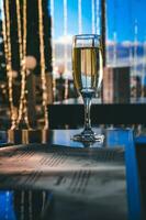 A glass of champagne in the table against the background of the bokeh of a night restaurant. Nightclub, celebration, christmas. photo