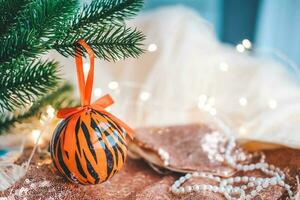 Christmas balls painted as tiger stripes on Christmas tree with a garland. 2022 is a year of the Tiger. Happy New Year . Symbol of year lunar chinese calendar tiger on Christmas ball . photo