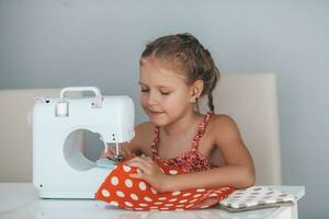 7 years old child studying work with a modern sewing machine. Hobby. photo