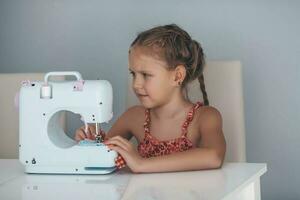 7 7 años antiguo niño estudiando trabajo con un moderno de coser máquina. pasatiempo. foto