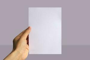 Realistic hand holding A5 paper mockup. Portrait A5 international paper size mockup. Simple, clean, modern, minimal paper mock up. Paper mockup in hand photo