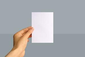 Realistic hand holding A6 paper mockup. Portrait A6 international paper size mockup. Simple, clean, modern, minimal paper mock up. Paper mockup in hand photo