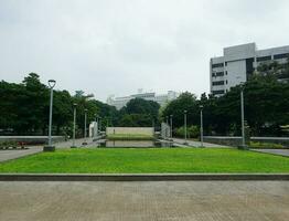 View of people watering the garden yard. This park is surrounded by greenery and several garden lampposts photo