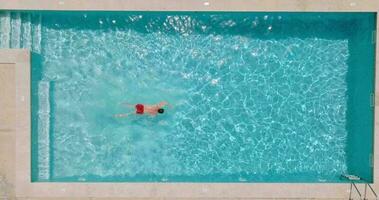 aéreo ver de un hombre en rojo pantalones cortos nadando en el piscina, lento movimiento. video