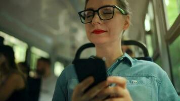 Öffentlichkeit Transport. Frau im Brille im Straßenbahn mit Smartphone. schleppend Bewegung video