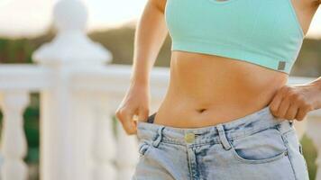 mujer disfrutar peso pérdida a hogar. hembra en antiguo pantalones después exitoso dieta. video