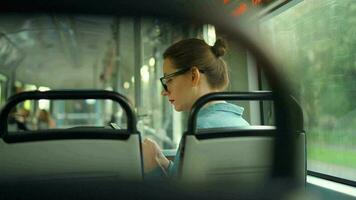 Publique transport. femme dans tram en utilisant téléphone intelligent, retour voir. video