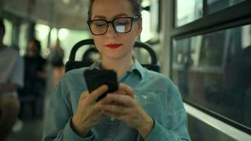 Public transport. Woman in glasses in tram using smartphone. Slow motion video