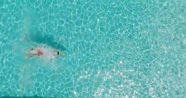 aéreo Visão Como uma homem mergulhos para dentro a piscina e nada, lento movimento video