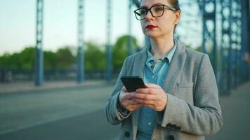 mujer en un Saco caminando alrededor el ciudad en el temprano Mañana con teléfono inteligente video