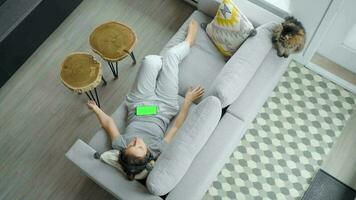 relaxado mulher dentro fones de ouvido com Smartphone com verde brincar tela video