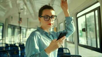 Public transport. Woman in glasses in tram using smartphone. video