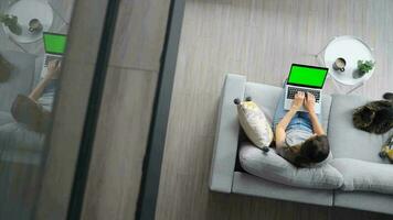 Overhead shot of woman using laptop with green mock-up screen video